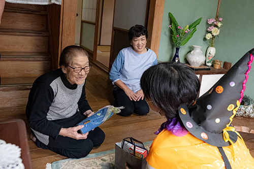敬老会のお祝いの品を渡す子ども