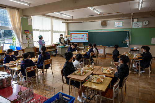 志麻さんフレンチ給食についての説明を聞く児童たち