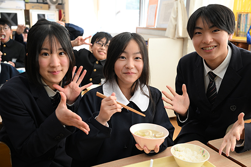 ふくつみれ鍋を持つ児童と山下さんと小林さん