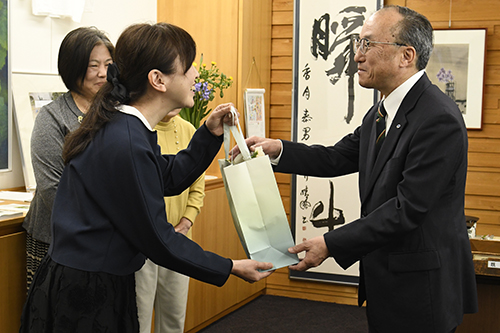生理用品の入った袋を江原会長（左）から受け取る伊藤教育長