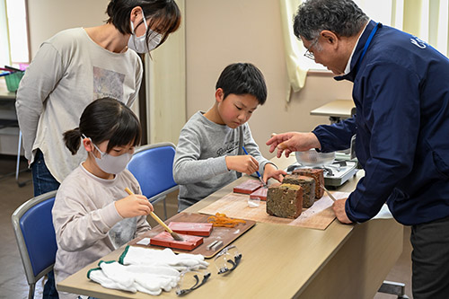 鋳造した銅剣を取り出しやすくするために鋳型にパウダーを塗る様子