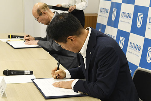 協定書に署名する江原市長（手前）と百瀬理事長