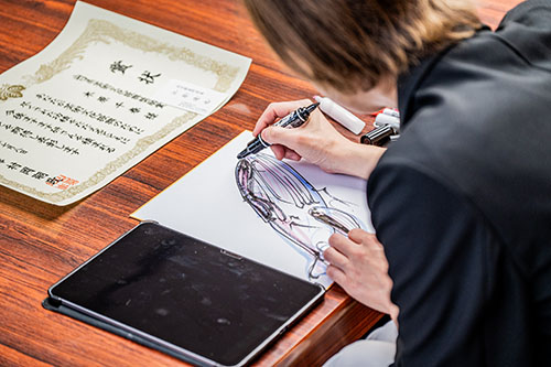色紙に長門市を象徴するくじらの絵を描く様子