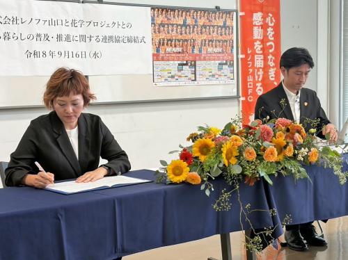 協定書に署名する末永代表幹事（左）と渡部社長