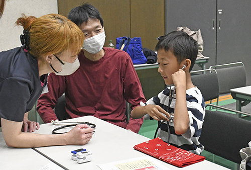 聴診器を使って看護師の業務を体験する親子