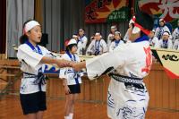 6年生から下級生に法被と太鼓のばちが引き継がれた