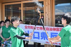 長門市役所市民広場で火を継ぐ様子
